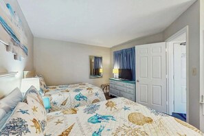 A hotel room with two beds, a TV, a dresser, and a door. - Ocean Forest Plaza 1213 (Myrtle Beach)