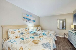 Ein Schlafzimmer mit einem Bett, Nachttischen, einer Kommode, einem Spiegel und einem Wandbild.