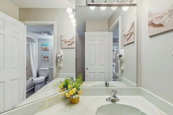 Un baño con un espejo grande, un lavamanos y una zona de ducha.