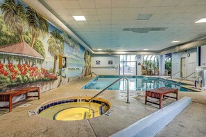 Ein Hallenbad mit Wandmalerei, Whirlpool und Sitzbank.