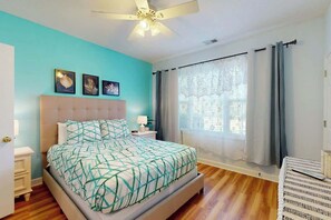 A bedroom with a bed, a nightstand, a ceiling fan, and a window with curtains. - Ironwood - Turtle Beach (North Myrtle Beach)