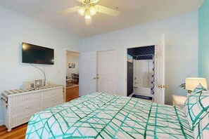 A bedroom with a bed, a dresser, a ceiling fan, a TV, and a door leading to another room. - Ironwood - Turtle Beach (North Myrtle Beach)