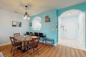 A dining area with a wooden table and chairs, a hanging light fixture, and a wall with a 'Beach House' sign. - Ironwood - Turtle Beach (North Myrtle Beach)