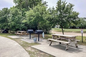 An outdoor picnic area with wooden tables and barbecue grills, surrounded by trees. - Ironwood - Turtle Beach (North Myrtle Beach)