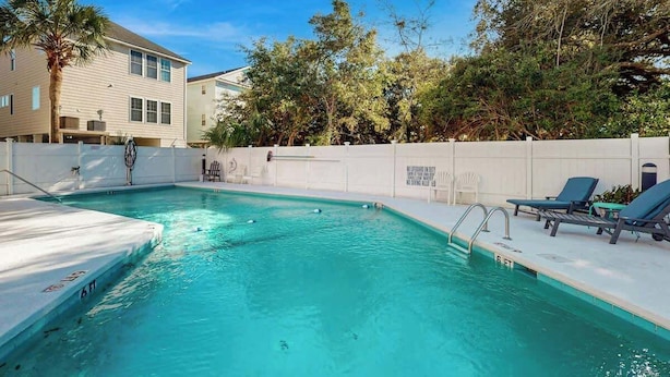 A swimming pool with a white deck, lounge chairs, and a white fence. - Live in the Sun, Play in the Sea (Surfside Beach)