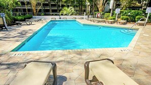 Une piscine avec des chaises longues et une terrasse carrelée.