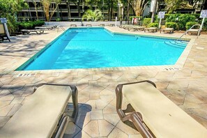 A swimming pool with lounge chairs and a tiled deck. - Sand Angels at Ocean Creek (Myrtle Beach)