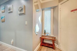 Un couloir orné d’œuvres d’art, un banc, une fenêtre donnant sur un paysage agréable et une porte sur laquelle est apposé un panneau « Interdiction de fumer ».