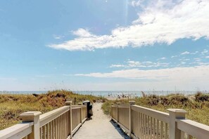 A wooden boardwalk leading to a beach with a clear sky. - Sand Angels at Ocean Creek (Myrtle Beach)