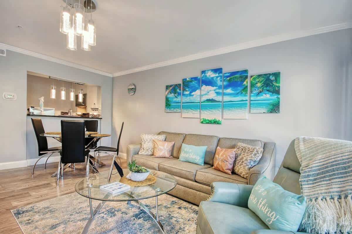 Un salon moderne avec une table basse en verre, un canapé agrémenté de coussins décoratifs et un coin repas comprenant une chaise et une table.