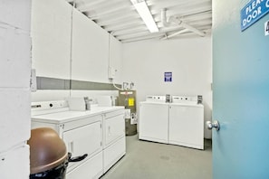 Ein sauberer, gut beleuchteter Hauswirtschaftsraum mit weißen Schränken, einem großen Warmwasserbereiter und einem Schild, das eine Tür anzeigt.