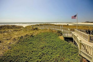 A wooden boardwalk leading to a beach with an American flag. - Sand Angels at Ocean Creek (Myrtle Beach)
