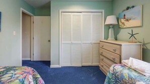 A bedroom with a closet, a dresser, a lamp, and a starfish decoration. - Summertree Village A-11 (Myrtle Beach)