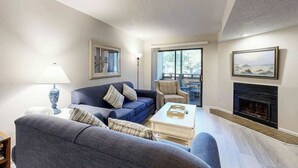 A living room with a sofa, armchairs, a coffee table, a fireplace, and a large window. - Summertree Village A-11 (Myrtle Beach)