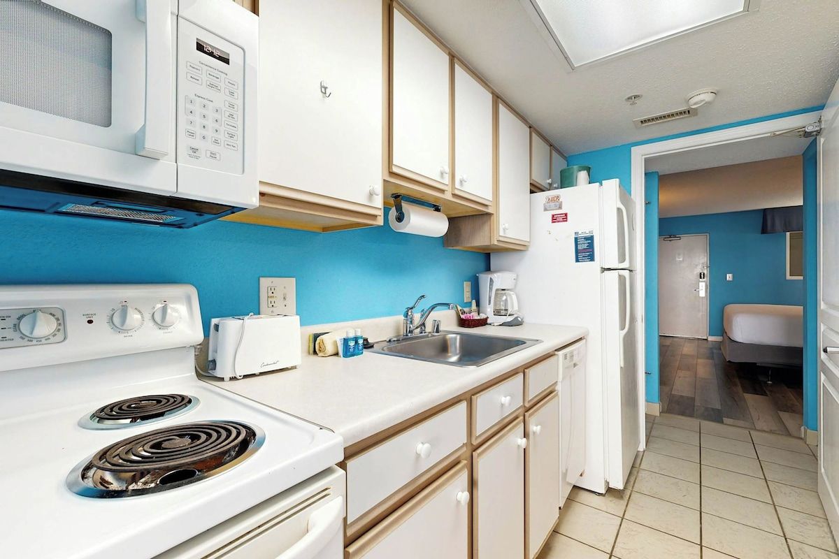 A kitchen with white appliances, a sink, and cabinets.