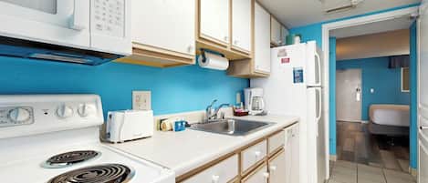 A kitchen with white appliances, a sink, and cabinets.