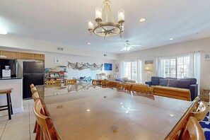 A spacious living area with a large dining table, a kitchen with modern appliances, and a ceiling fan. - Coconut Grove Unit 202 (North Myrtle Beach)