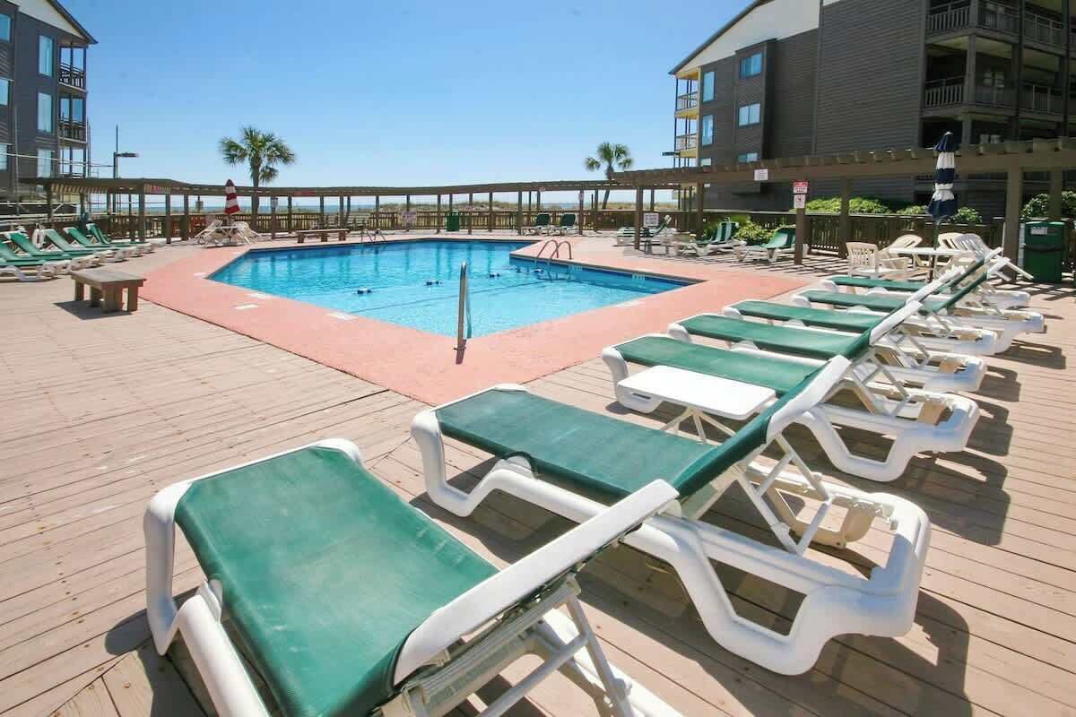 A pool area with lounge chairs and a wooden deck.
