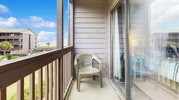 A balcony with a view of a building and a chair. - Tilghman Beach & Racquet 214 (North Myrtle Beach)