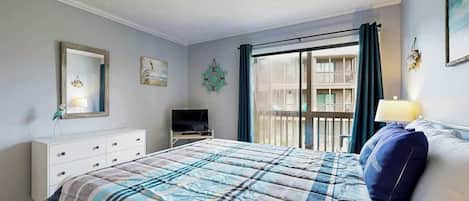 A bedroom with a bed, a dresser, a television, and a window with curtains.
