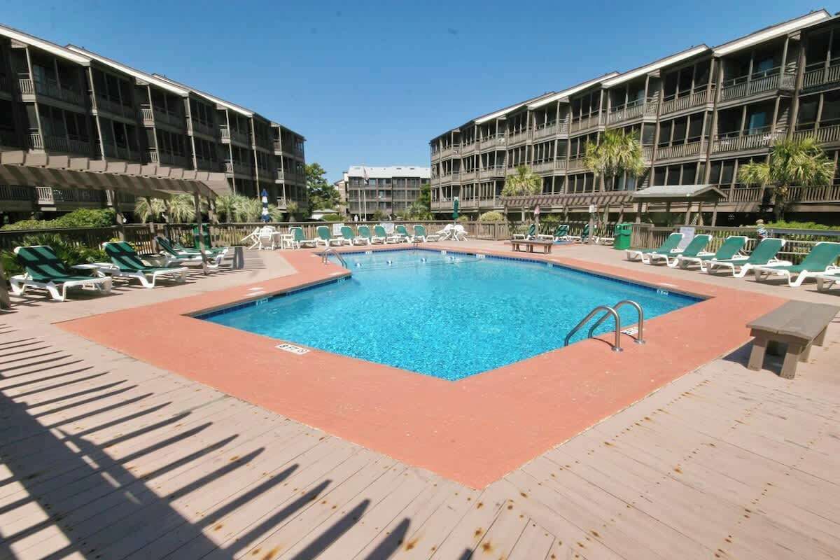 A swimming pool with lounge chairs and a wooden deck.