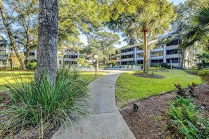 A pathway leading to a building with multiple floors, surrounded by greenery and trees. - Summertree Village D-4 (Myrtle Beach)