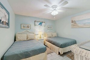 Ein Schlafzimmer mit zwei Betten, einem Deckenventilator und Bildern an den Wänden.