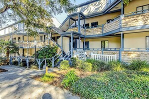 A multi-story building with a stone facade, outdoor stairs, and a landscaped garden area. - Summertree Village D-4 (Myrtle Beach)