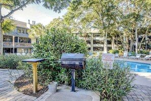 A poolside area with a barbecue grill, a sign prohibiting charcoal, and a pool. - Summertree Village D-4 (Myrtle Beach)