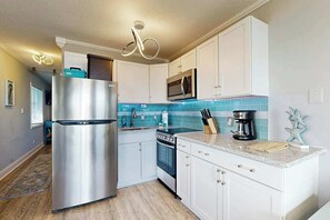 A modern kitchen with white cabinets, stainless steel appliances, and a blue backsplash. - Breathtaking Beach Views (North Myrtle Beach)