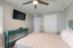 A bedroom with a bed, a ceiling fan, a television mounted on the wall, and a door. - Breathtaking Beach Views (North Myrtle Beach)