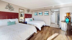A hotel room with two beds, a wooden floor, a kitchen area, and a hallway leading to other rooms. - Caravelle Resort 206 (Myrtle Beach)