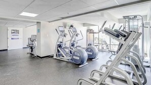 A gym with exercise equipment, a door with a sign, and a window allowing natural light. - Caravelle Resort 206 (Myrtle Beach)