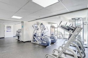 A gym with exercise equipment, a door with a sign, and a window allowing natural light. - Caravelle Resort 206 (Myrtle Beach)
