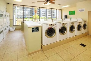 A laundry room with multiple washing machines, a closed sign, and a view of buildings outside. - Myrtle Beach Resort A-544 (Myrtle Beach)