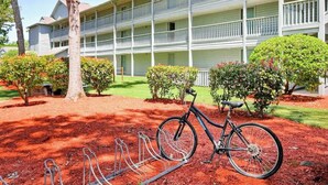 Un immeuble à plusieurs étages avec un porte-vélos devant.