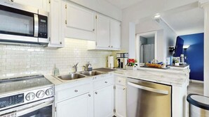 Une cuisine moderne avec des meubles blancs, un four à micro-ondes en acier inoxydable, un four encastré, un lave-vaisselle et un plan de travail en marbre.