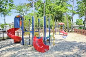 A playground with a red slide, climbing structures, and a red canopy shelter. - Myrtle Beach Resort A-544 (Myrtle Beach)