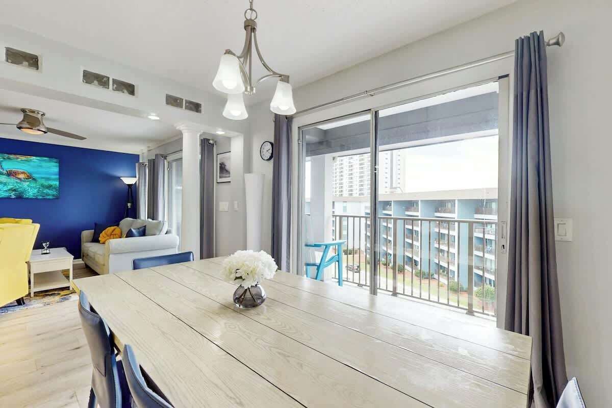 A modern living room with a dining table, a sofa, and a balcony with a view of the city.