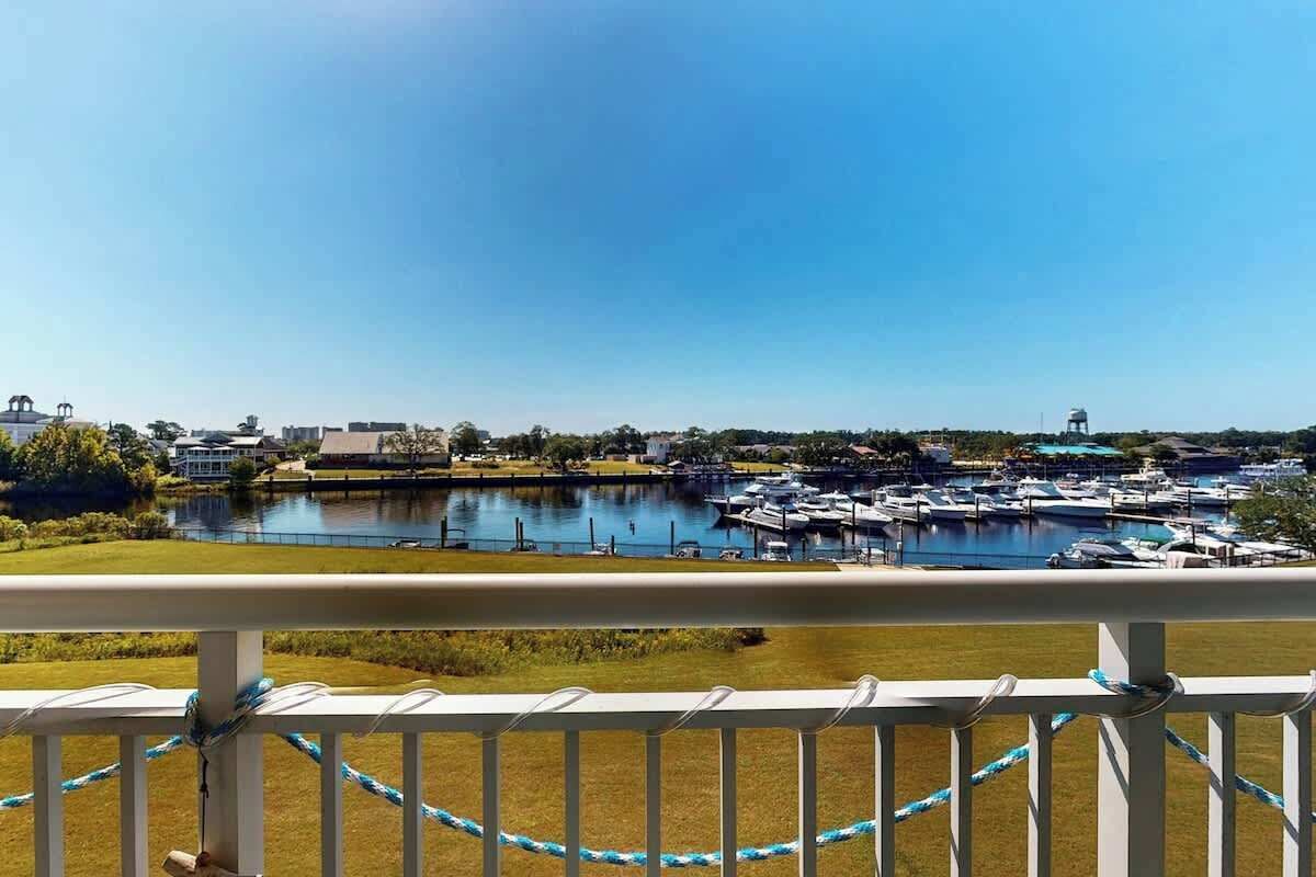 Een jachthaven met afgemeerde boten, een heldere lucht en een uitzicht op gebouwen in de verte.