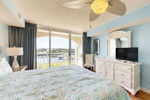 Un dormitorio con cama, cómoda, televisor y balcón con vistas.