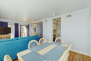 A room with a dining table, chairs, a sofa, and a television. - Ocean Bridge Unit 4-B19 (Myrtle Beach)