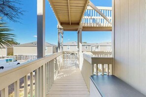 A wooden deck with railings, leading to a covered area with a view of neighboring houses. - Ocean Bridge Unit 4-B19 (Myrtle Beach)