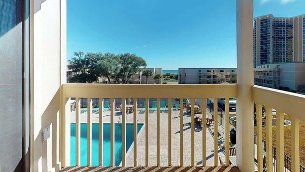 A balcony with a view of a swimming pool and surrounding buildings. - Ocean Bridge Unit 4-B19 (Myrtle Beach)