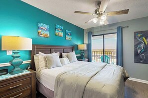 A bedroom with a bed, two bedside lamps, a ceiling fan, and artwork on the walls. - Renaissance Tower 915 (Myrtle Beach)