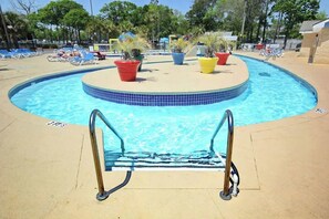 A swimming pool with a tiled edge, surrounded by lounge chairs and potted plants. - Renaissance Tower 915 (Myrtle Beach)