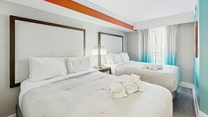 A hotel room with two beds, a nightstand, a lamp, and a view of the outdoors. - Grande Cayman Unit 1057 (Myrtle Beach)