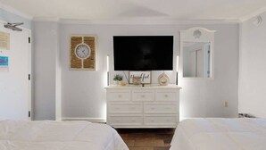 A bedroom with a white dresser, a flat-screen TV, a clock, and a mirror. - Monterey Bay Unit 823 (Myrtle Beach)