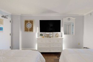 Ein Schlafzimmer mit weißem Schminktisch, einem Flachbildfernseher, einer Uhr und einem Spiegel.