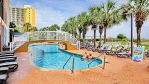 A swimming pool with a bridge, lounge chairs, and palm trees. - Monterey Bay Unit 823 (Myrtle Beach)